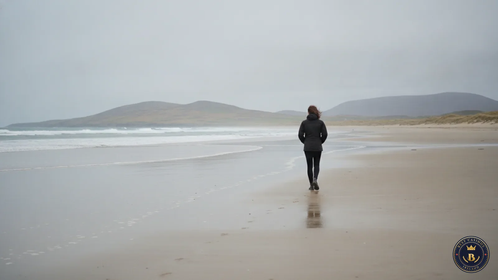 Person walking alone on a wide Connemara beach on a grey, breezy day